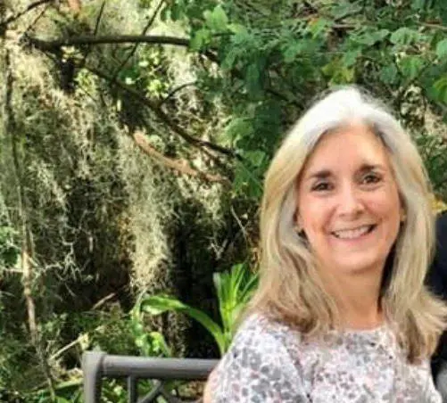 A woman sitting in front of some trees